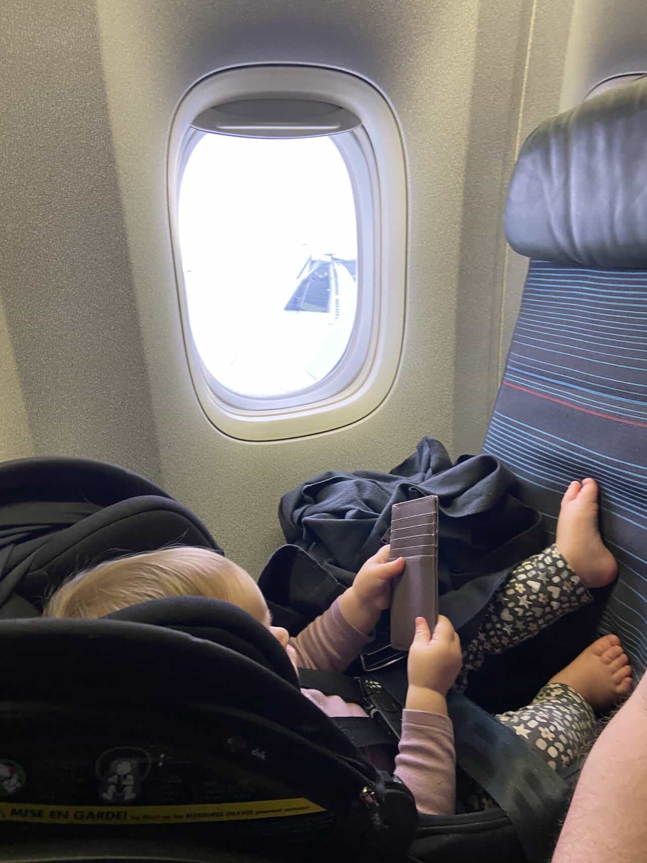Tips for Flying With a Baby: From Booking to Baggage Claim 7 Baby C in her car seat on the airplane playing with mom's wallet