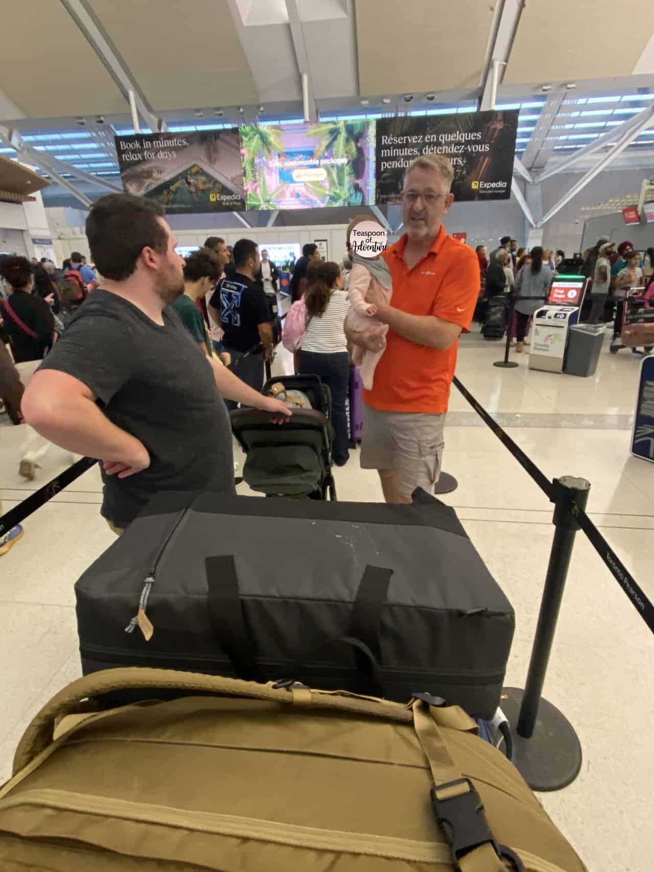 Tips for Flying With a Baby: From Booking to Baggage Claim 19 Standing in line at YYZ airport with our suitcases and travel crib
