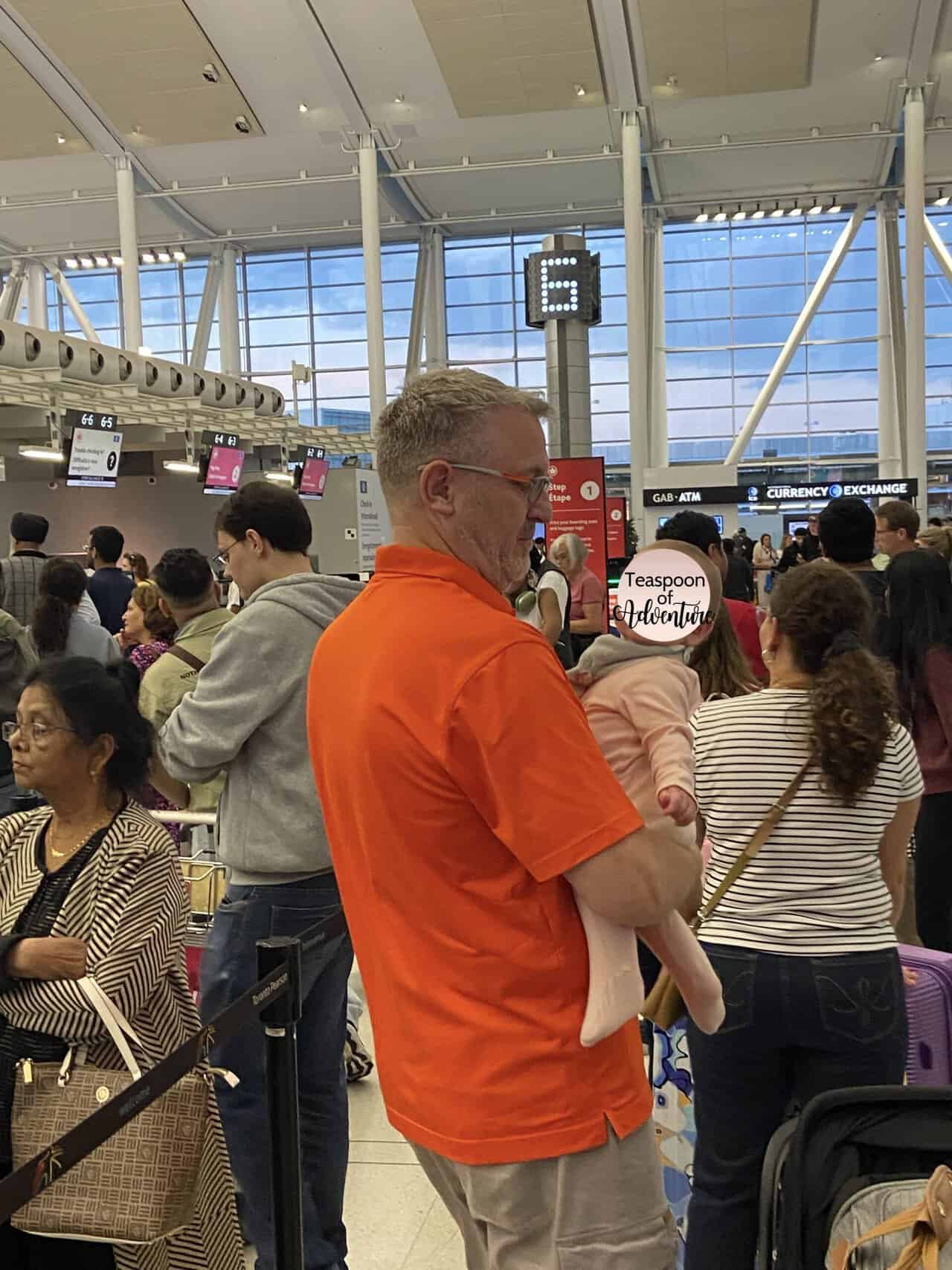 Tips for Flying With a Baby: From Booking to Baggage Claim 26 Baby C and Riana's dad, Jeff, standing in line to check in at YYZ Airport in Toronto