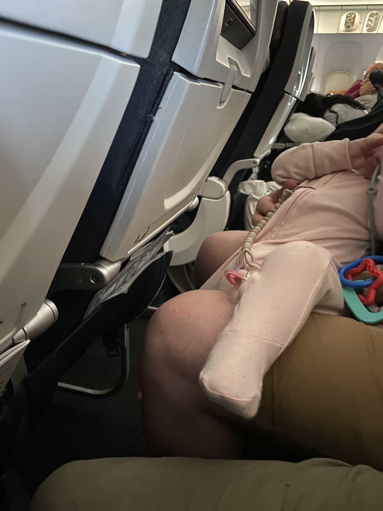 Tips for Flying With a Baby: From Booking to Baggage Claim 21 Baby C in her sleeper sitting on Colin's lap on our flight to Paris