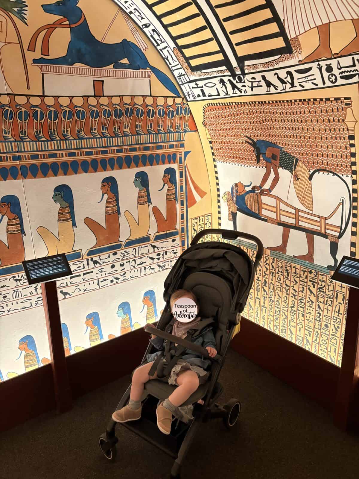 Baby C in her stroller inside a colourful Ancient Egyptian tomb in the Royal BC Museum
