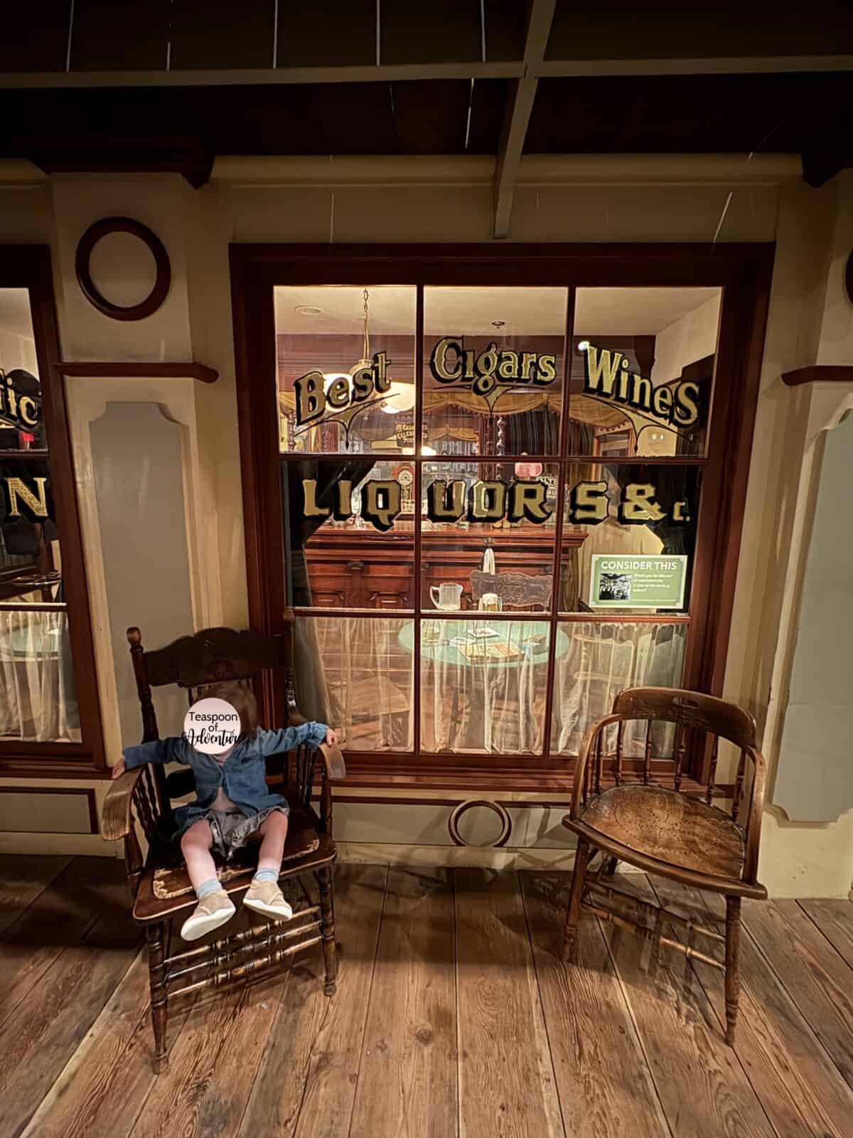 C sitting in a chair outside a shopfront in Old Town, New Approach at the Royal BC Museum