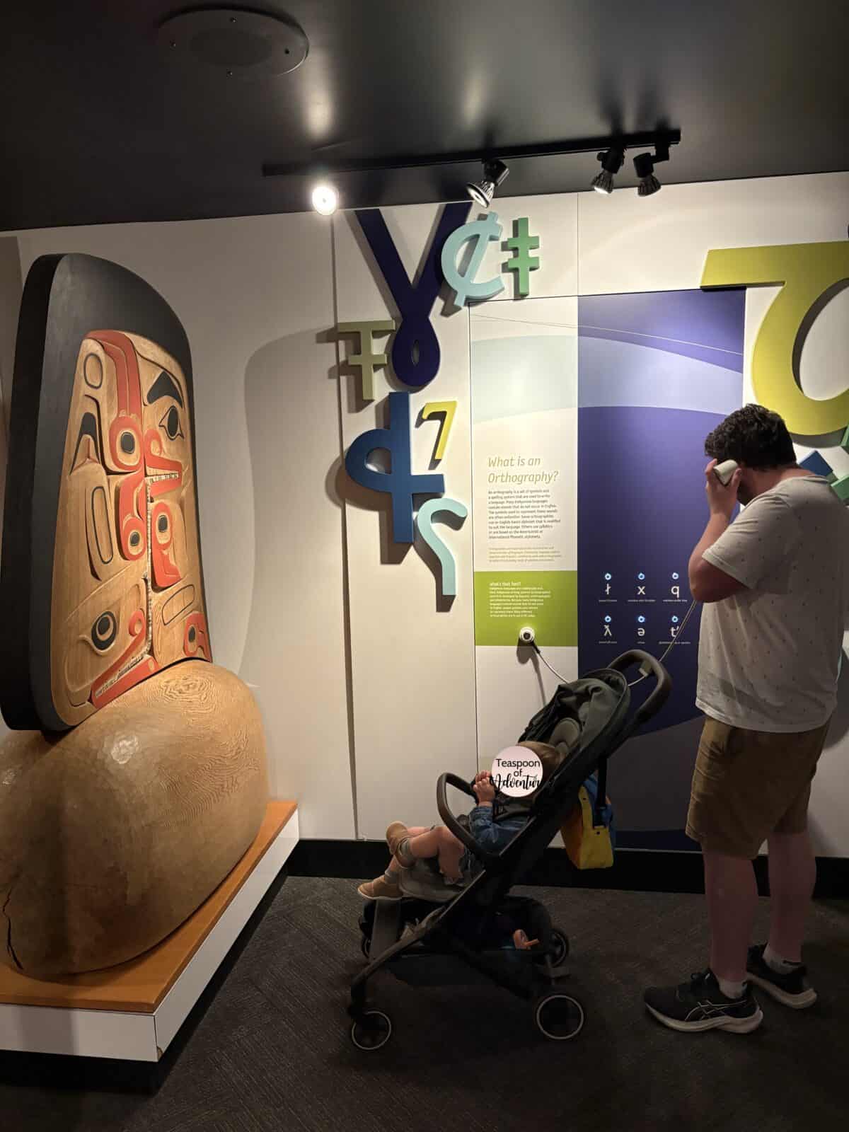 Colin and C in her stroller checking out the Interactive displays at Our Living Languages at Royal BC Museum