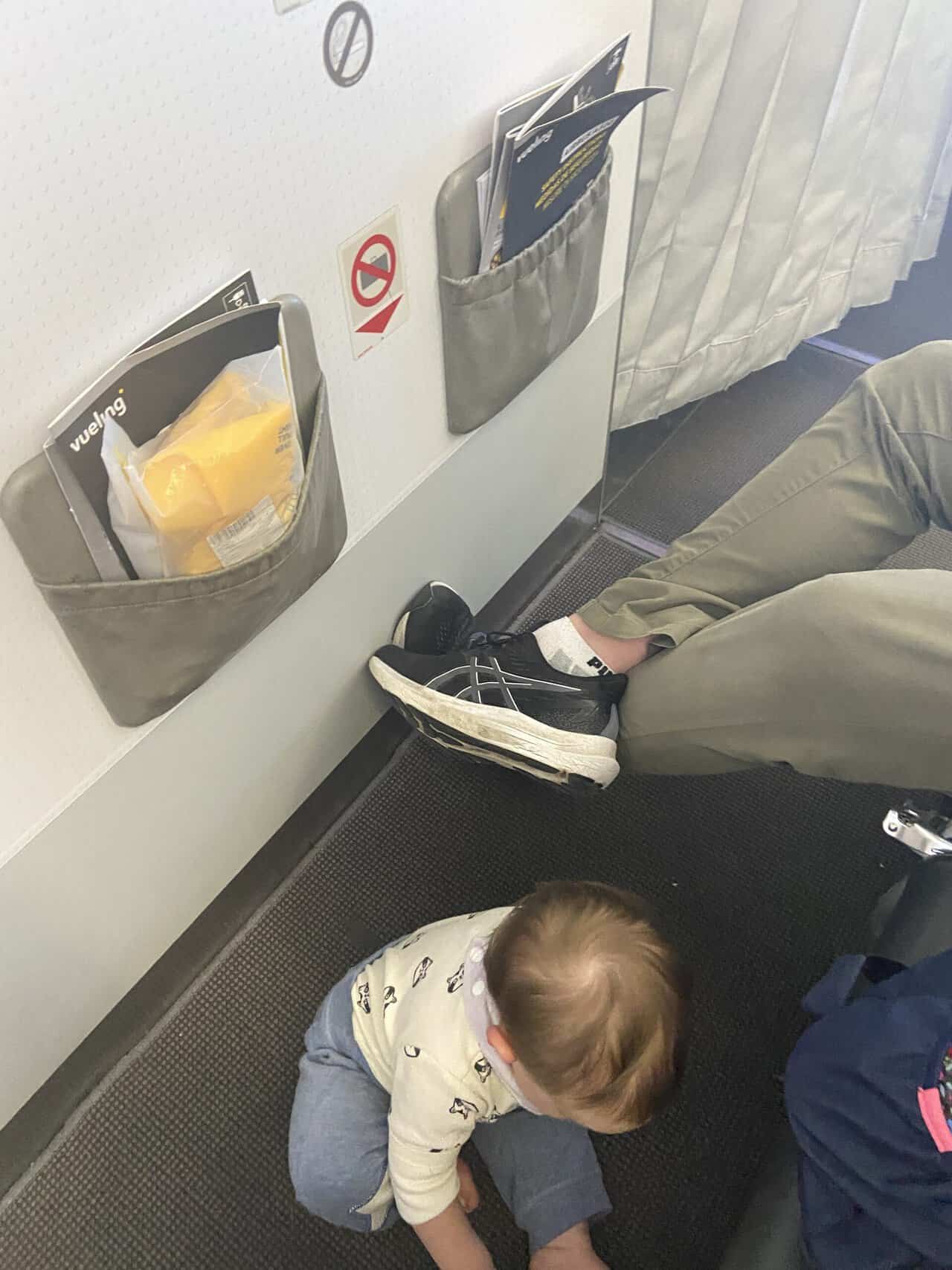 Tips for Flying With a Baby: From Booking to Baggage Claim 12 Bulkhead row of the airplane with Colin's feet outstretched and Baby C playing on the floor