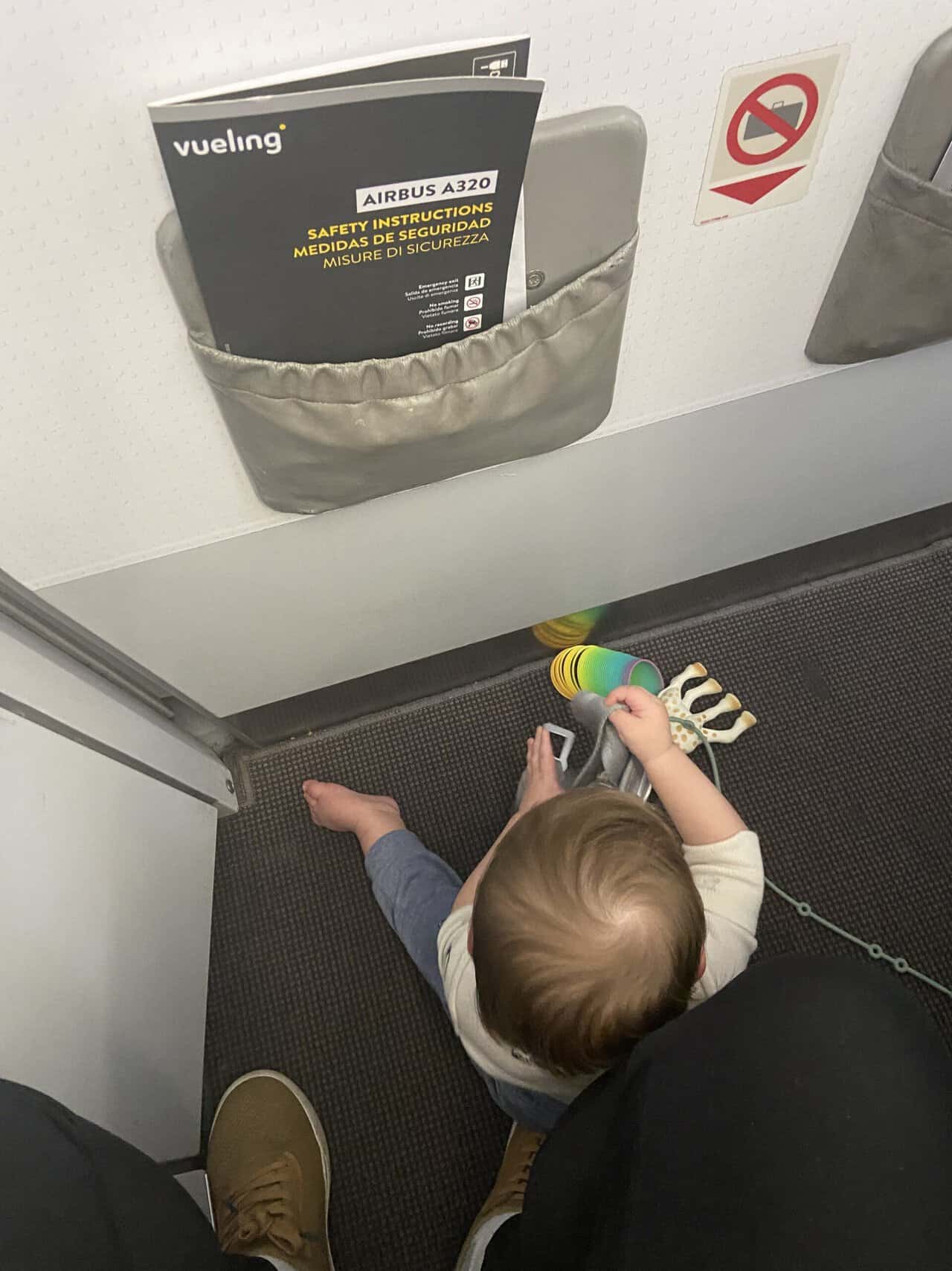 Tips for Flying With a Baby: From Booking to Baggage Claim 45 Baby C playing with toys on the floor of our bulkhead row on the plane