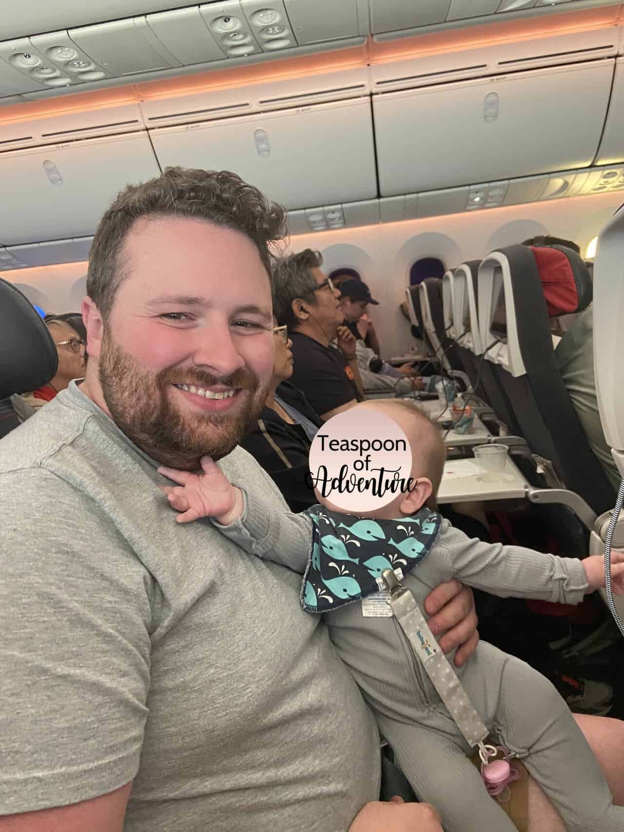 Tips for Flying With a Baby: From Booking to Baggage Claim 8 Baby C sitting on Colin's lap during a flight