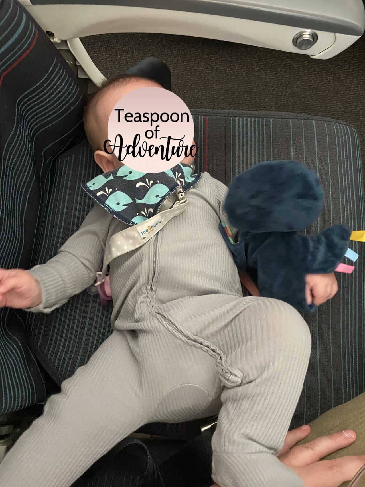 Tips for Flying With a Baby: From Booking to Baggage Claim 25 Baby C in a long sleeve sleeper lying on an airplane seat