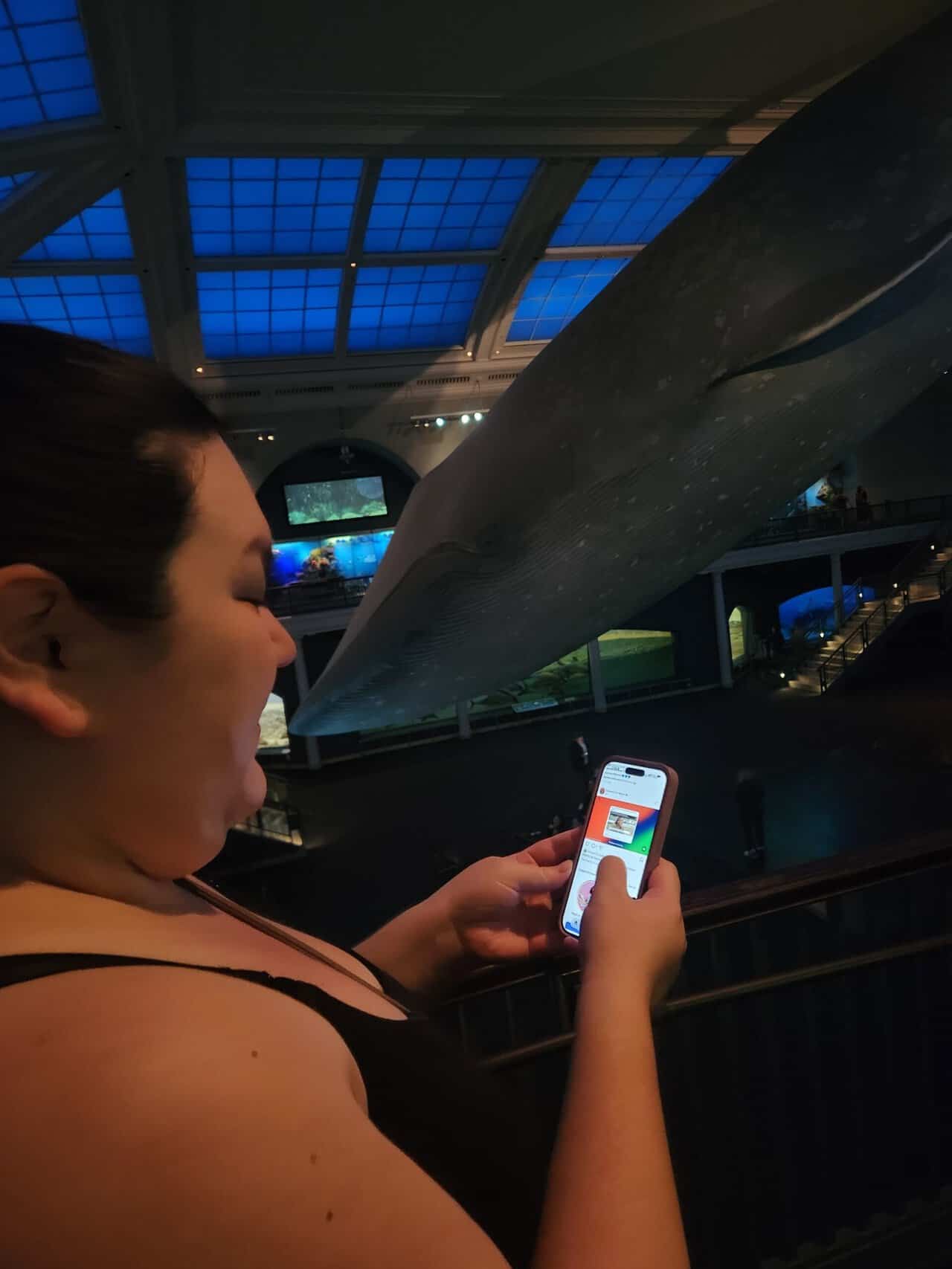 RIana using her phone in front of the big blue whale at the American Museum of Natural History in New York City