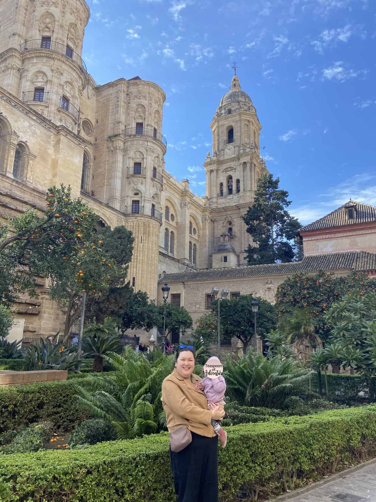 Riana holding C in front of the Malaga Cathedral in Malaga, Spain